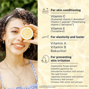 Woman holding a lemon slice next to a list of vitamins and extracts for skincare benefits.